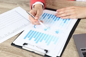 Budget planning. Woman with papers at wooden table, closeup