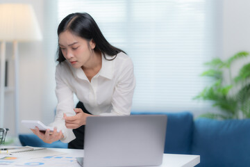 Asian businesswomen working in the office talking the phone, and checking the report