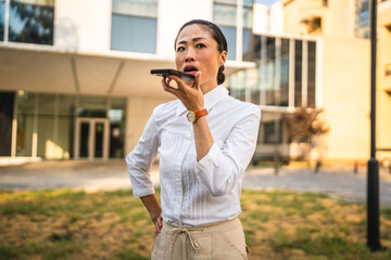 Angry mature japanese business woman record voice mail on mobile phone