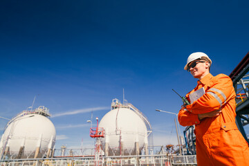 A professional engineer in protective gear, including a hard hat and orange coveralls, inspects a...