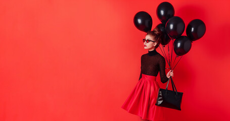 Fototapeta premium Black Friday promotion background template with a stylish woman in a red skirt and black top holding black balloons and a handbag, standing against a red background