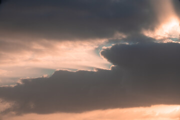 The sky is filled with clouds and the sun is setting. The clouds are dark and the sky is a mix of...