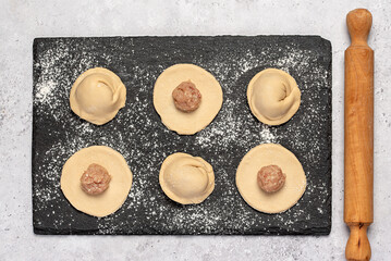 Macro food photography of ingredients of  homemade dumplings, raw dough and minced chicken, onion, ravioli, tortellini, rolling pin