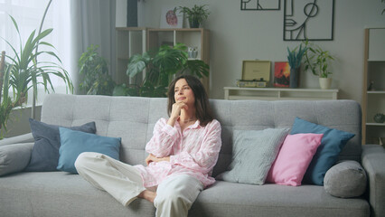 Woman sitting on sofa at home thinking and