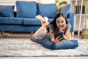 Obraz premium Young woman relaxing on floor at home using smartphone