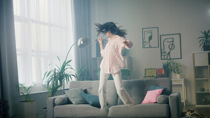 Carefree woman dancing on the couch at home
