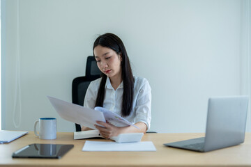 Asian businesswoman reading documents in modern office