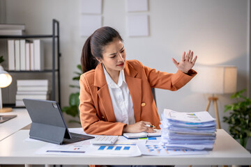 Stressed asian accountant refusing more work at office desk