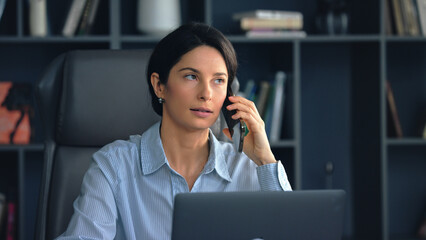 Businesswoman talking on phone while working on