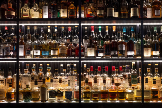 Inverness, Scotland - 12 August 2024: shelf of Scottish whiskey bottles in modern dark bar