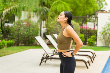 Young athletic woman taking a breather after outdoor workout by the pool