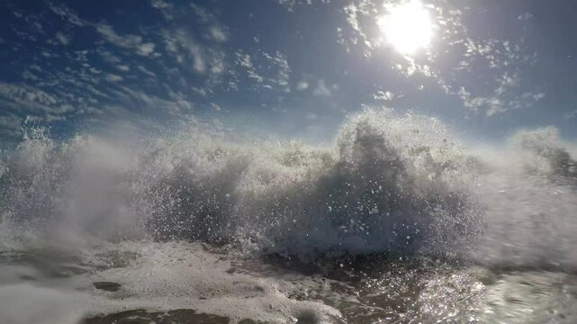 A wave in the ocean crashes into the camera