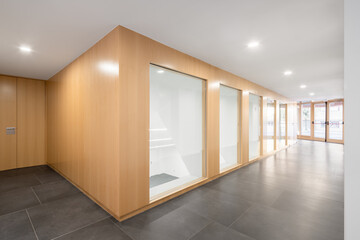 Modern auditorium hallway with wooden panels and glass doors