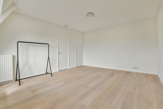 Spacious and empty room with wooden floor and white walls