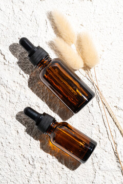 Two amber glass bottles with essential oils on stone surface