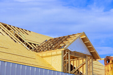 Obraz premium Placing plywood on wooden roofing trusses at assembled roof of house in construction