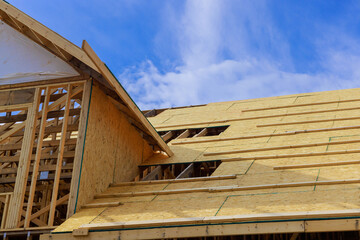Obraz premium Plywood is installed on wooden roofing trusses at assembled roof of house in construction