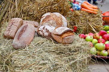 A rustic display of various artisan breads placed on straw, showcasing the textures and natural...