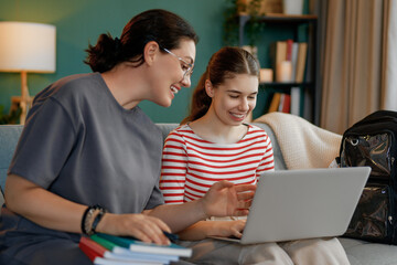 Happy child and her mother are sitting on sofa