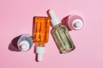 Top view of serum dropper bottles on a pink background