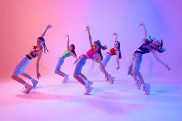 Wandcirkels Dansschool With grace and intensity, dancers bring their choreography to life on stage in neon light against gradient pink background. Concept of sport and hobby, childhood, friendship, motion. Dance school.  © Lustre Art Group 