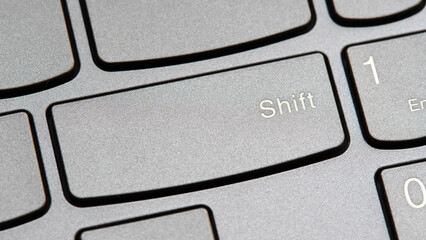 Man pressing the shift key on a modern laptop computer keyboard closeup top view, one person. Shift button key, shifting changing simple abstract concept, capital letters, special characters symbol