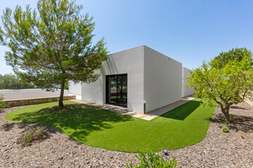 Modern minimalist house with synthetic lawn and mature trees