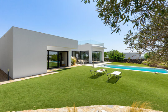 Modern home with pool and large garden under blue sky