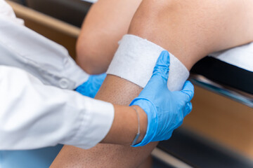 Hospital bandage on the knee. Specialist doctor cures injured knee