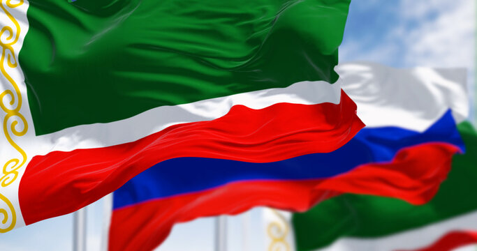 Flags of Chechnya and Russia waving in the wind on a clear day