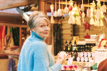 Outdoor portrait of beautiful middle age woman with grey hair buying gifts and souvenirs at...