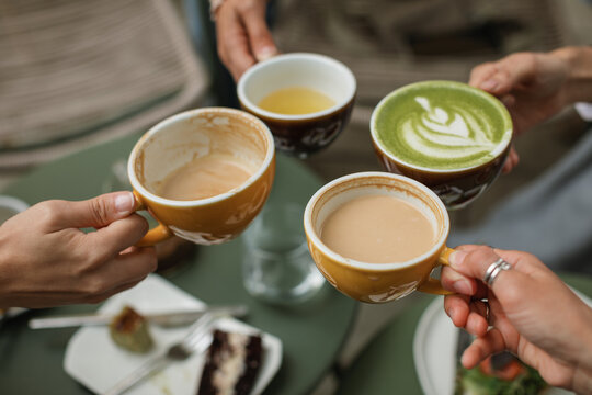 Four friends gather for breakfast in a cozy cafe enjoying buckwheat tea, cappuccino, matcha latte. - Powered by Adobe
