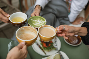 Four friends gather together for breakfast at a cafe sharing hot drinks.