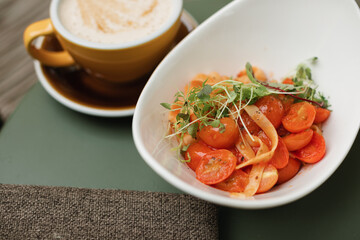 Italian pasta with tomatoes and shrimp, garnished with microgreens, on a beautiful plate, served on the summer terrace.
