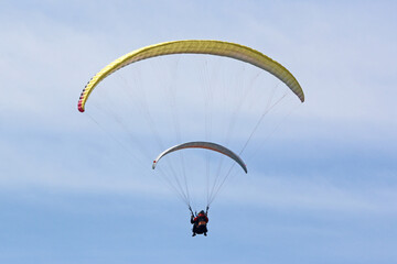 Tandem Paraglider flying in a cloudy sky	
