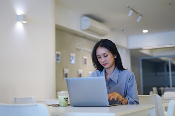 Concentrated attractive businesswoman working with laptop at modern office