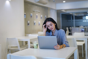 Obraz premium Young asian woman having migraine and headache while trying to work online front of laptop