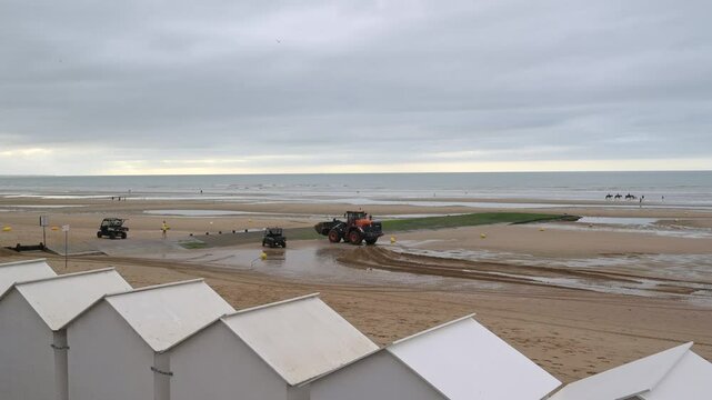 Beach, city of Cabourg, Normandy, a backhoe moves sand near the beach cabins, High quality 4k footage