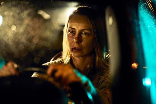 Woman driving at night with bruises on face