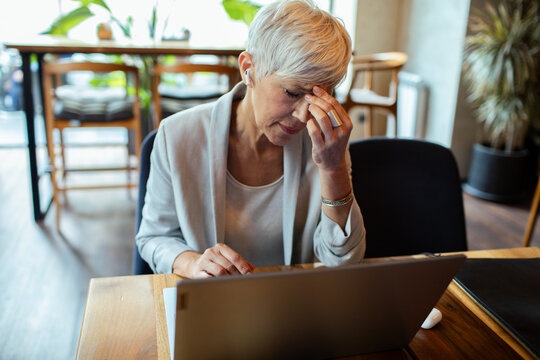 Stressed professional senior woman using laptop in cafe