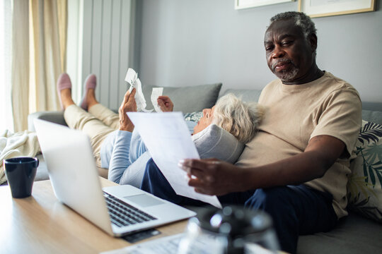Diverse senior couple reading bills on the couch at home
