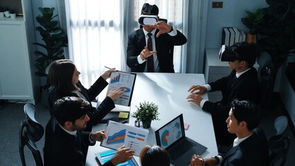 Top view of manager working on laptop and sending data analysis to business people by using VR glass headset while diverse team planning marketing strategy and looking at financial graph. Directorate.