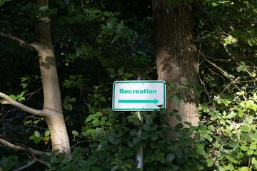 Picture of a green framed sign with a white base and the inscription recreation in a dense forest