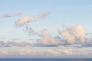 blue sky with puffy clouds lightened by rising sun