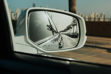 Reflection of a scenic road with palm trees in car side mirror with coastal drive vibes