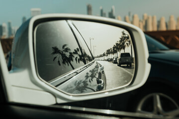 Reflection of a scenic road with palm trees in car side mirror with coastal drive vibes
