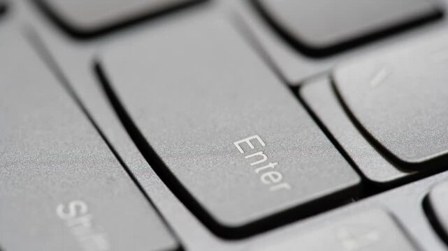 Man quickly pressing the enter key on a modern laptop computer keyboard, macro detail extreme closeup, shallow DOF, one person. Sending a message, buying, accepting rules, running a program concept