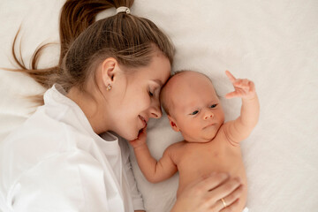 a mother with a newborn baby, a young mother gently hugs and kisses her newborn son, a space for text, a happy family and maternal love and care