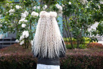 Female back with long, curly, blonde hair, on natural park background
