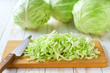 Whole and sliced fresh green cabbage on a cutting board, selective focus.